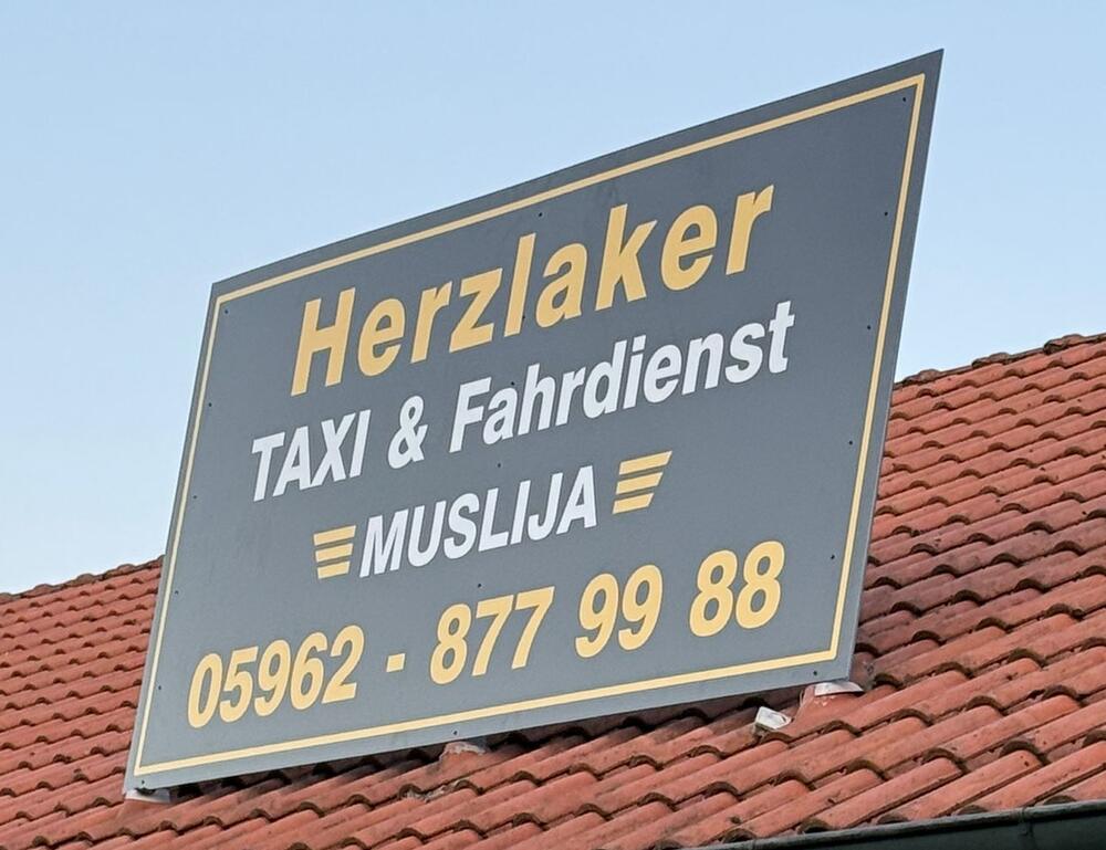 Firmenschild: Herzlaker Taxi und Fahrdienst Muslija, Telefon 05962 877 99 88